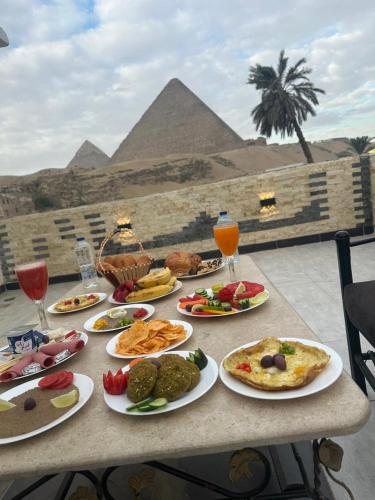 een tafel met borden met eten erop met de piramides bij Pyramids essence view in Caïro