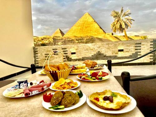 een tafel met borden met eten en de piramides bij Pyramids essence view in Caïro