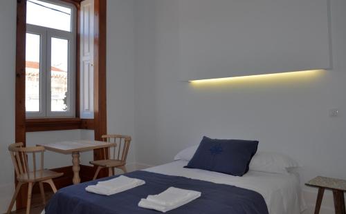a bedroom with a bed and a table with chairs at Casa de São Bento by PURUS in Coimbra