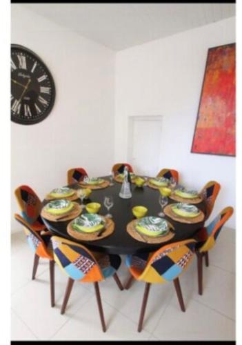 ein Esstisch mit Stühlen und einer Uhr an der Wand in der Unterkunft Maison de village familiale Sablet in Sablet