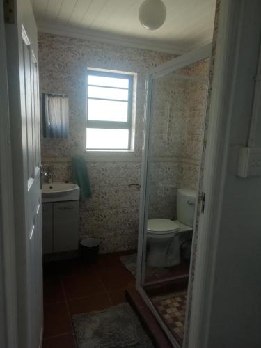 a bathroom with a toilet and a sink and a window at PauMar Guesthouse in Sutherland