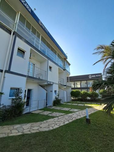 een groot wit gebouw met een palmboom ervoor bij Pousada Mar Alto in Ilha Comprida