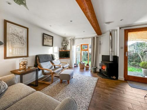 een woonkamer met een bank en een open haard bij Pilsbury Cottage in Luppitt
