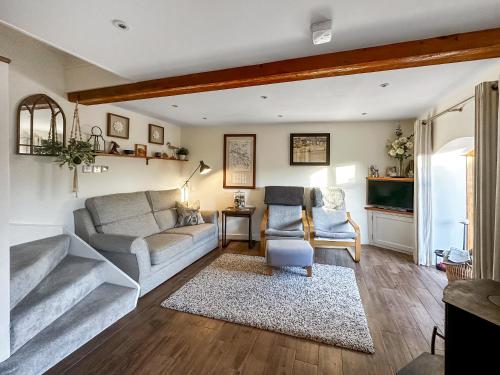 een woonkamer met een bank en twee stoelen bij Pilsbury Cottage in Luppitt