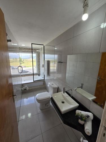 a white bathroom with a toilet and a sink at Pousada Mar Alto in Ilha Comprida