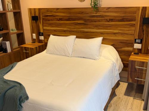プラヤ・デル・カルメンにあるStudio de luxe Duna 206の白いベッド1台が備わる木製の壁のベッドルーム1室