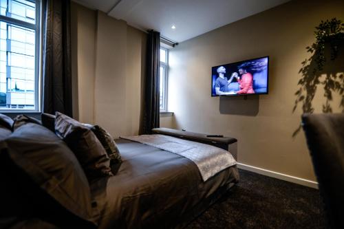 a bedroom with a bed and a tv on the wall at Ladywell House Suites in Birmingham