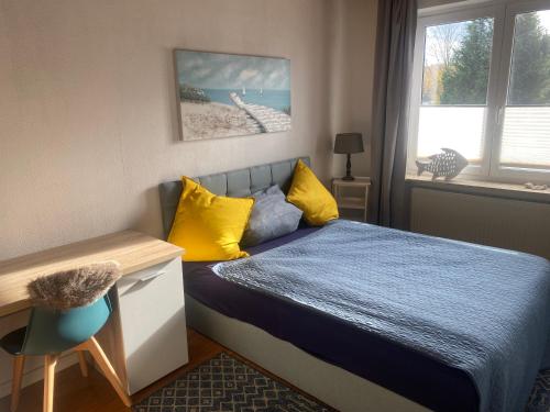 a bedroom with a bed with yellow pillows and a desk at Apartment am Waldrand in Itzehoe