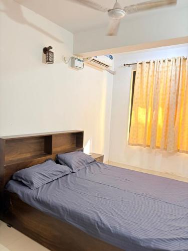 a bedroom with a bed with blue sheets and a window at Square Greens in Siolim