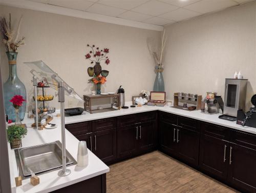 een keuken met bruine kasten en witte aanrechtbladen bij Best Western Plus Miamisburg-Dayton Suites, Banquets & Hotel in Miamisburg