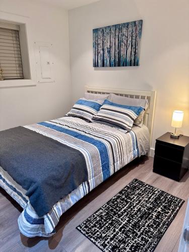 a bedroom with a bed with a blue and white blanket at A&A Resident - Modern North Vancouver 2BR Suite in North Vancouver