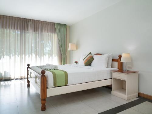 a bedroom with a bed and a large window at Amphawaree Hotel in Samut Songkhram