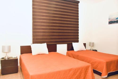2 letti con lenzuola arancioni in una camera di Paraiso apartment 1 a Playa del Carmen
