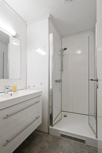 a white bathroom with a shower and a sink at Premium House Øvre Langgate 27 in Tønsberg
