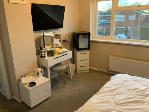 a bedroom with a bed and a desk with a television at Apps B&B in Poole