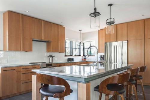 a kitchen with wooden cabinets and a large island with bar chairs at Stay at Old Garden Beach in Rockport
