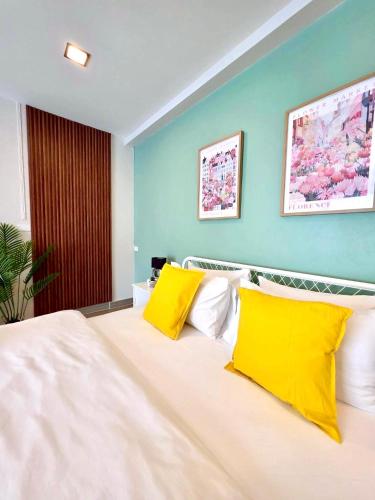 ein Schlafzimmer mit einem großen weißen Bett mit gelben Kissen in der Unterkunft The See Stay Hatyai in Hat Yai