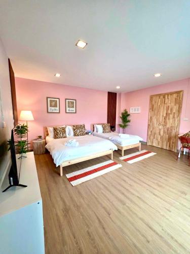 a bedroom with two beds and a pink wall at The See Stay Hatyai in Hat Yai