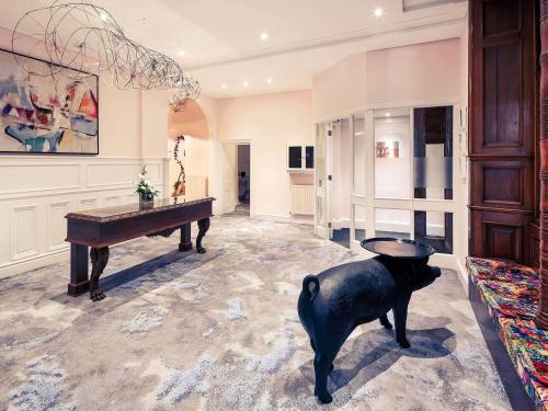格洛斯特格洛斯特鲍顿大厦美居酒店的房间里有一架钢琴和一尊狗的雕像