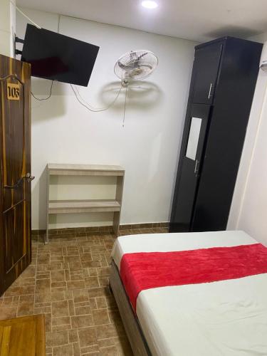 een slaapkamer met een bed en een ventilator aan de muur bij Hostal Casa Roma in Taganga