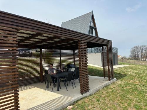 een man zittend aan een tafel onder een houten pergola bij Wine Valley Villas in Lipovac