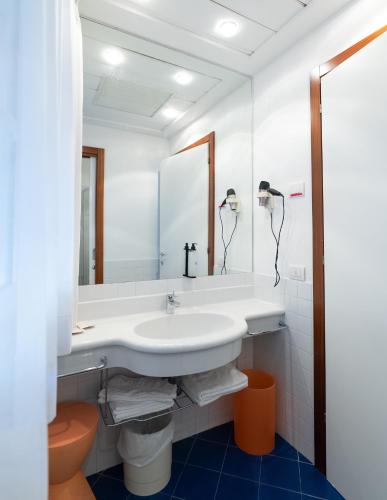 a white bathroom with a sink and a mirror at Residence Adriatico in Gabicce Mare