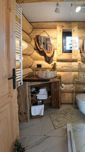 a log bathroom with a sink and a mirror at Cabana de la Stână in Râşnov