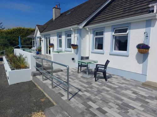 een huis met een terras met een tafel en stoelen bij Rest a While in Bushmills