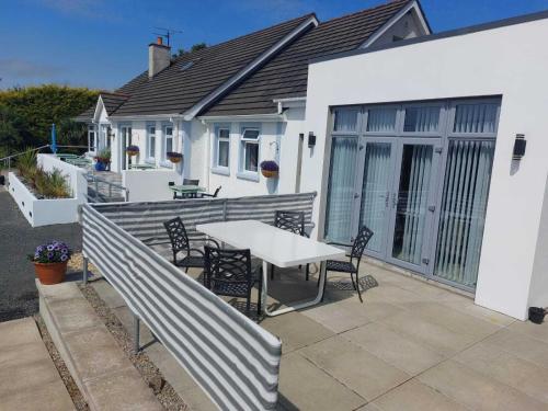 een terras met een tafel en stoelen voor een huis bij Rest a While in Bushmills