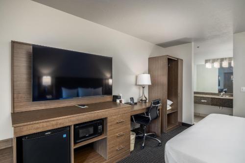 a hotel room with a desk with a large television at St. George Inn and Suites in St. George