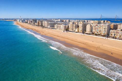 eine Luftaufnahme eines Strandes mit Gebäuden und dem Meer in der Unterkunft Cadiz Playa 3 Rooms in Cádiz