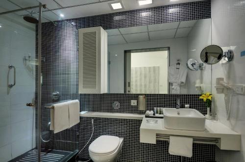 a bathroom with a sink and a toilet and a mirror at Grand Mercure Bangalore - An Accor Brand in Bengaluru