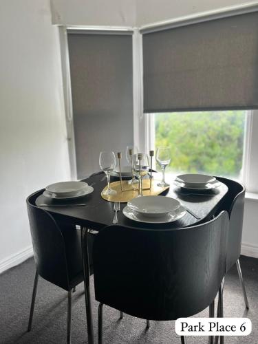 a black table with chairs and plates and wine glasses at Park Place Apartments in Sunderland