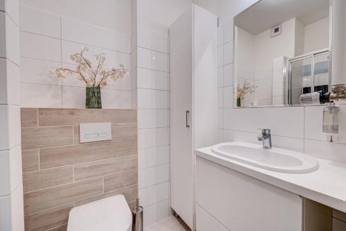 a white bathroom with a toilet and a sink at Apartamenty Aquamarina Onyx - visitopl in Międzyzdroje