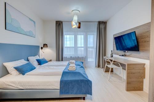 a bedroom with a bed and a desk with a television at Apartamenty Aquamarina Onyx - visitopl in Międzyzdroje