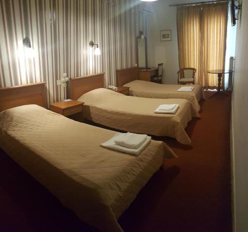 a hotel room with four beds with towels on them at Hotel Liberty in Mesolongion