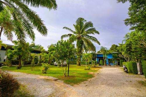 a house with palm trees and a dirt road at Little Purple House- AoNang in Ao Nang 