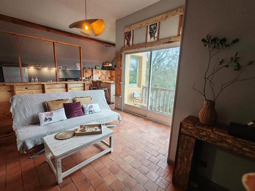 ein Wohnzimmer mit Sofa und Tisch in der Unterkunft Maison à 5mn de Honfleur in Fourneville