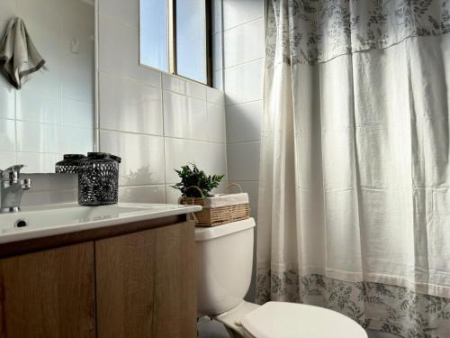 a bathroom with a toilet and a sink and a shower curtain at Arden Haus Estadías boutique Talca in Talca