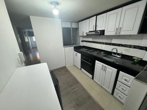 a kitchen with white cabinets and a sink and a stove at Espectacular Apartamento 1-6 huéspedes in Tunja