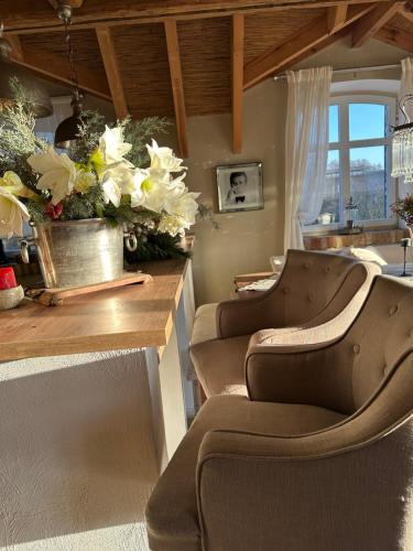 een woonkamer met 2 stoelen en een tafel met bloemen bij Cottage am Rosencarree in Beelitz