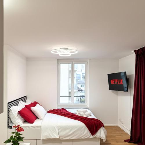 a bedroom with a bed with red pillows and a window at Pop-up design studio Workplace central location in St. Gallen