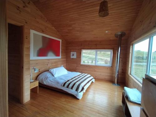 ein Schlafzimmer mit einem Bett in einem Holzzimmer in der Unterkunft Casa Azul Frutillar in Frutillar