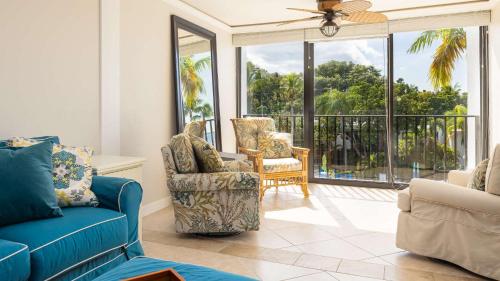 a living room with a blue couch and chairs and windows at Tranquility at MoonBay B - 304 in Key Largo