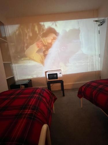 a room with two beds and a large screen at Flexy Students Room 1 in Gloucestershire
