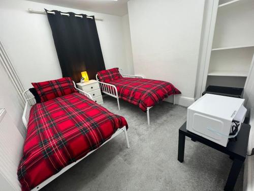 a bedroom with two beds and a red blanket at Flexy Students Room 1 in Gloucestershire