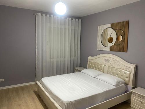 een slaapkamer met een wit bed en een spiegel bij Cherry Apartments in Shkodër