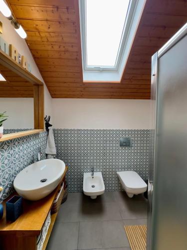 a bathroom with a sink and a toilet and a skylight at Casa de Sub Munte Cozy Chalet in Fundata