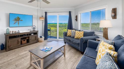 a living room with a blue couch and a tv at Saltair Loft Ocean Pointe 2 BR 2 BA 1411 in Tavernier