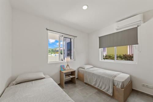 two beds in a room with two windows at Apartement Ocean Hibiscus, Punta Azul Ocean Resort, Westpunt in Lagun